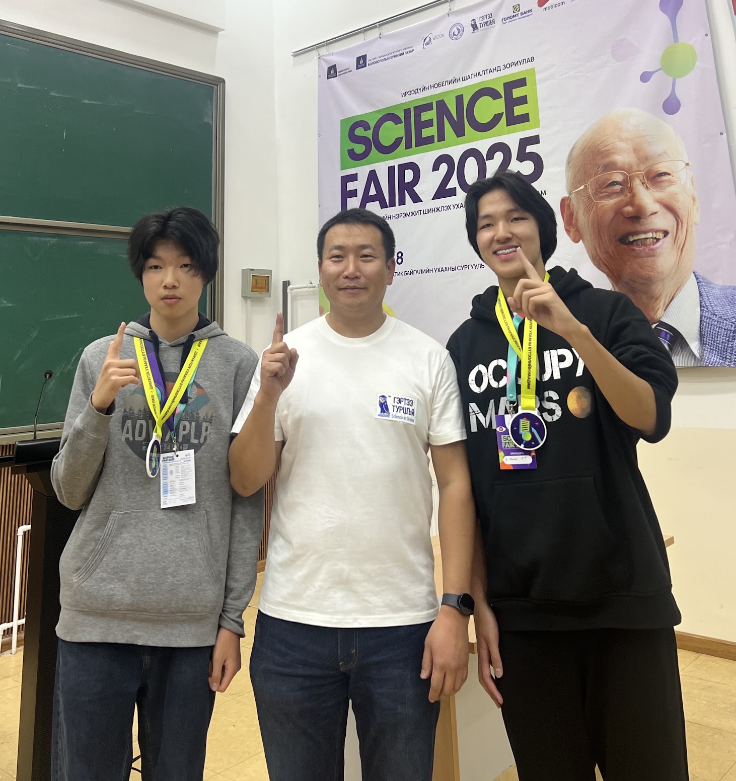 Itgel and teammates wearing medals in front of a Science Fair 2025 banner