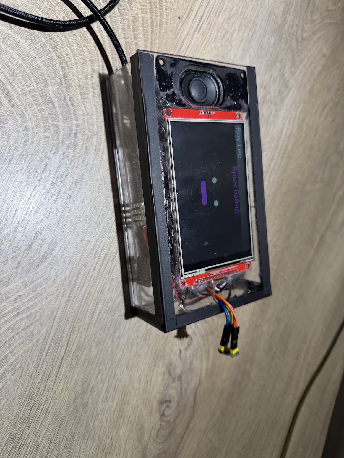 The finished RoyLee device, screen on, mounted on a wall